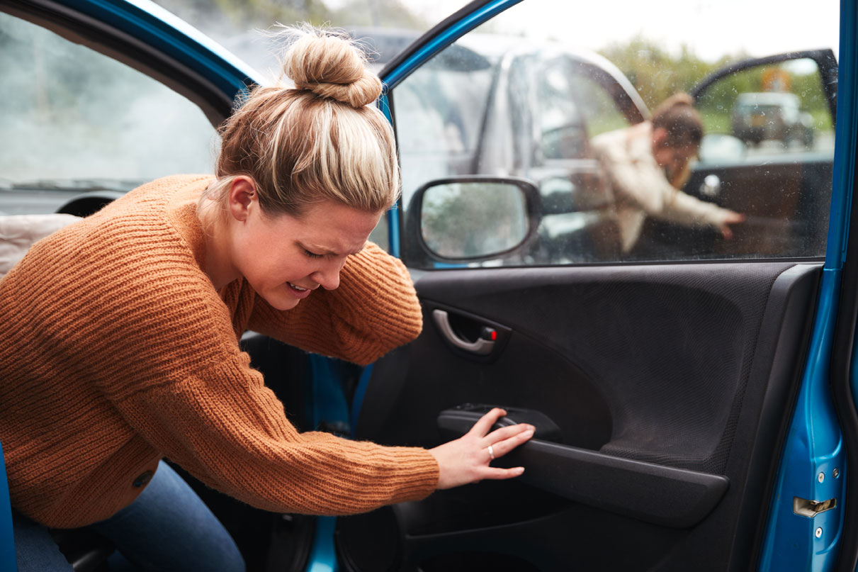 woman holding neck while getting out of car