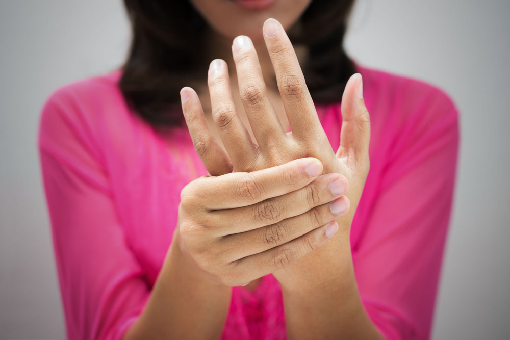 woman squeezing one hand, showing pain the hands