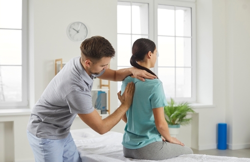 Female patient undergoing back adjustment by chiropractor.