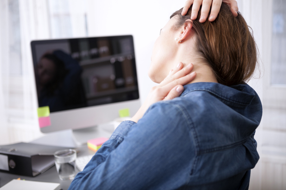 Woman with neck pain while at work, needs chiropractic care in Livonia.