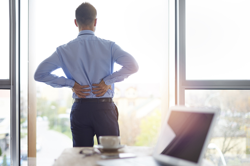 man suffering from scoliosis at work