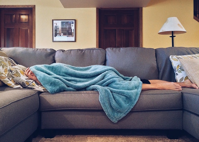 person laying under blanket on couch