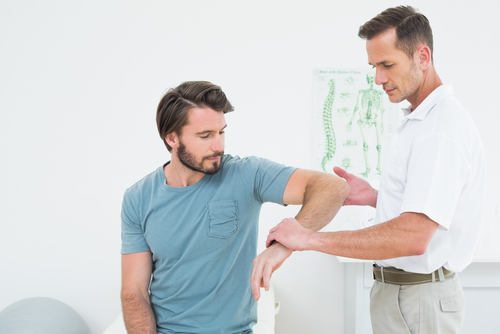 Chiropractor examining patient’s elbow for pain and mobility issues during chiropractic care