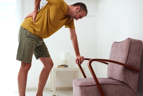 Man holding lower back in pain caused by sciatica