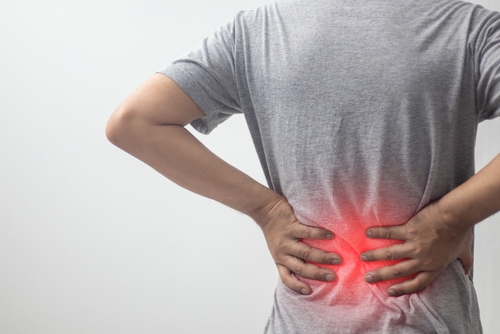 Man holding lower back in pain due to muscle strain or injury