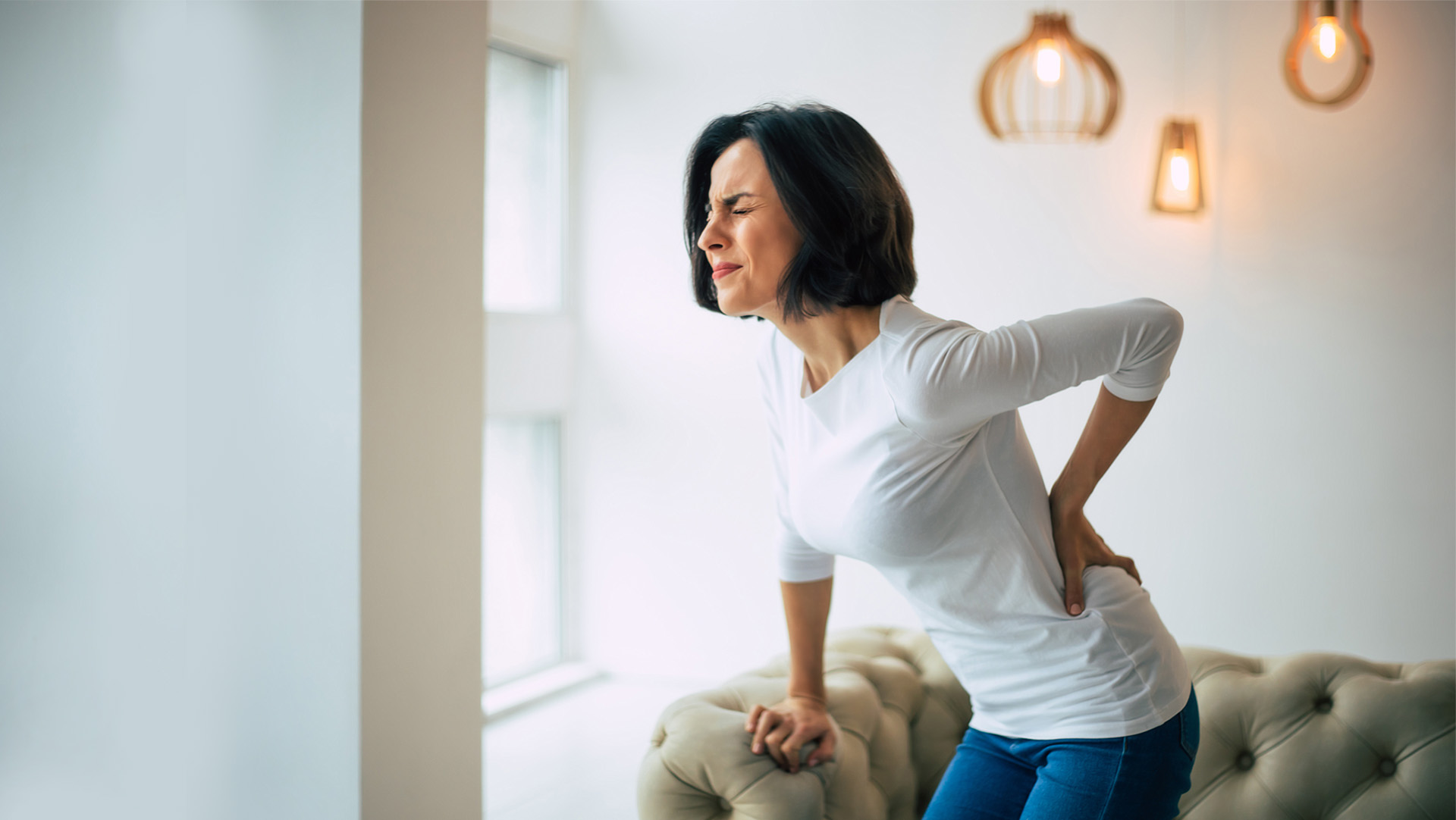 Woman bending over with low back pain Woman bending over with low back pain