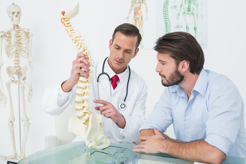 doctor showing spine model to a patient